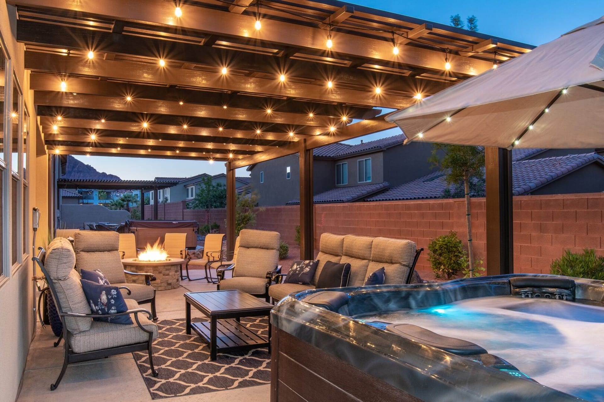 Covered patio with a fire pit and private hot tub at Sunshine Suites